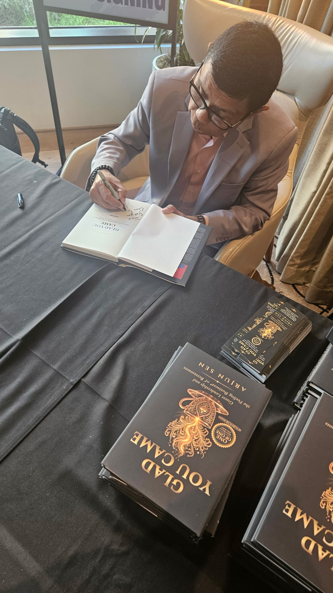 Arjun Sen signing a copy of Glad You Came at a book signing